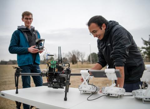Larkin Heintzman (left) and Pratik Mukherjee, both doctoral students in the Department of Electrical and Computer Engineering, calibrate several drones before flying them at Virginia Tech's drone park. Photo: Virginia Tech